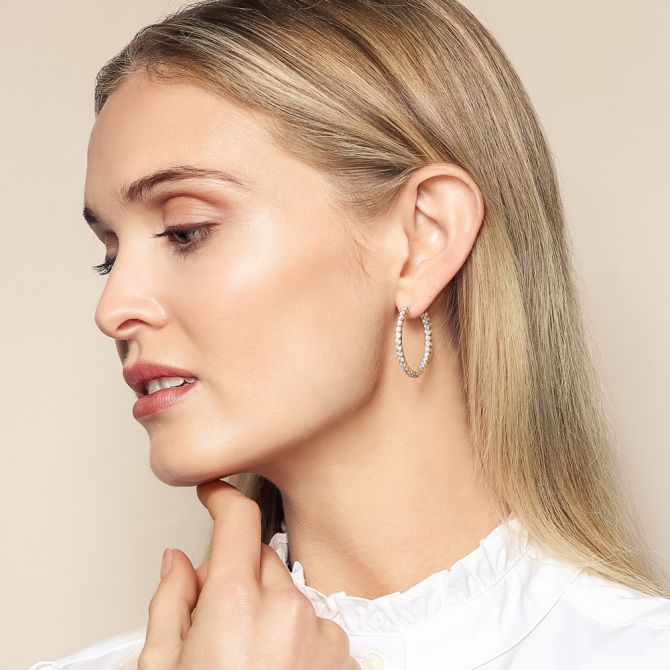 Woman wearing 3 cttw yellow gold inside out diamond hoops