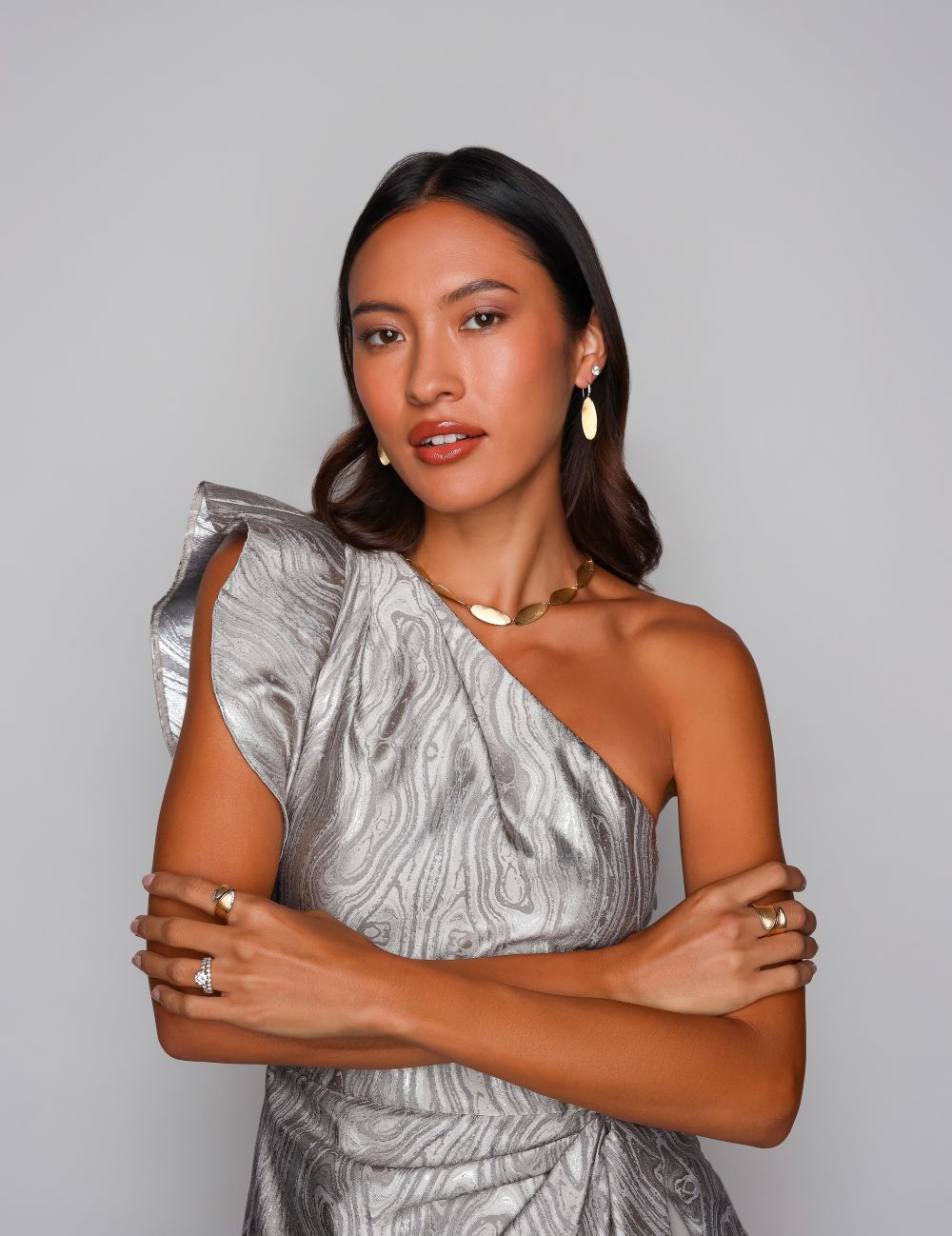 Female wearing gold jewelry with a silver black tie dress